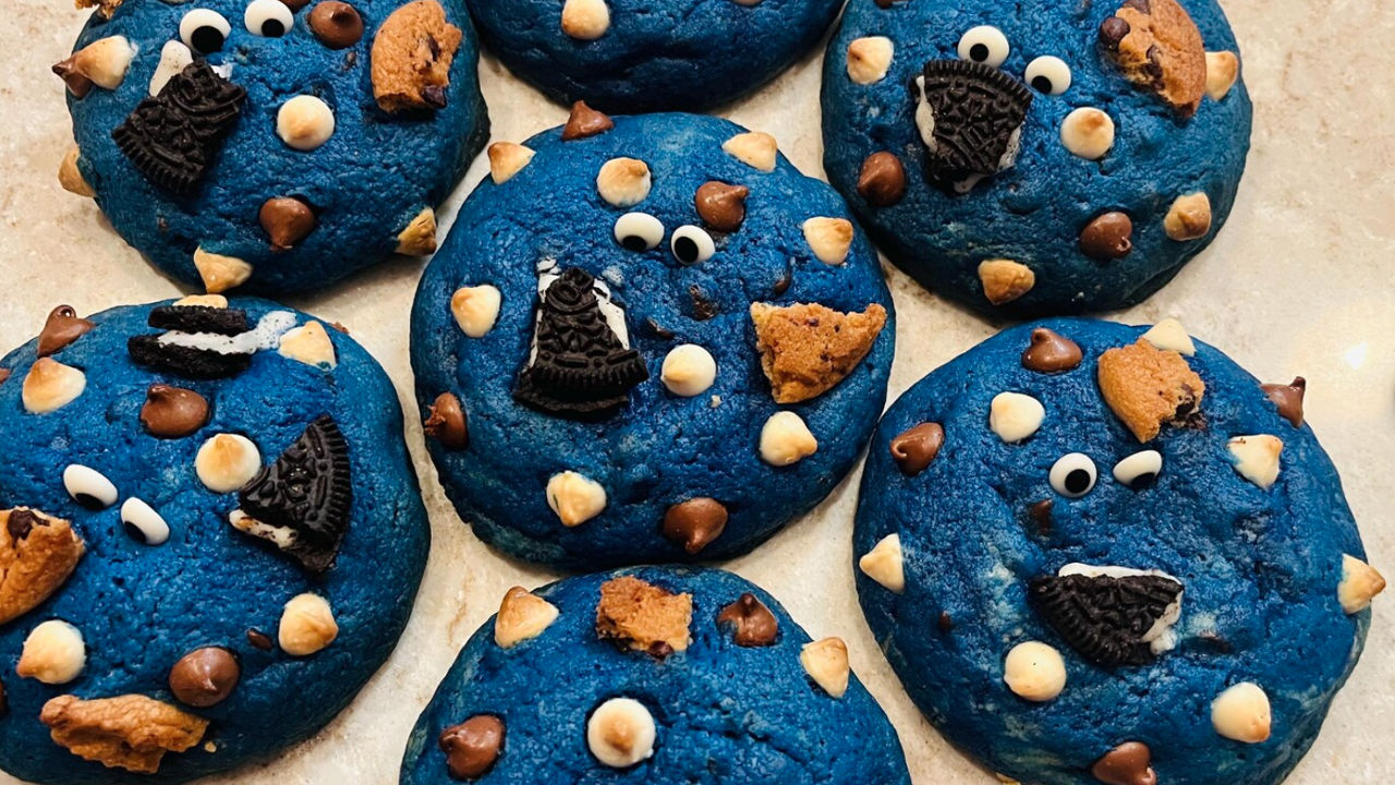 Blue Cookie Monster-themed cookies with chocolate chips, white chips, cookie pieces, and candy eyes