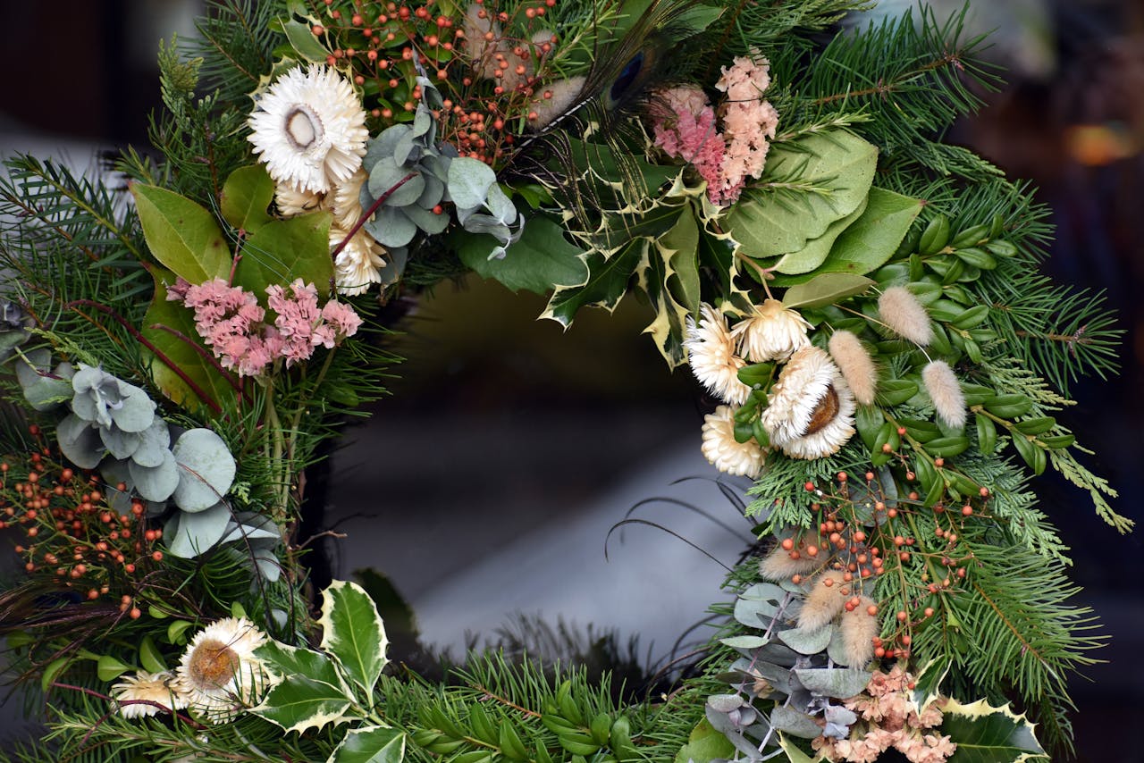 DIY floral wreath made from dried flowers, pine, eucalyptus, and holly leaves arranged in a circular design