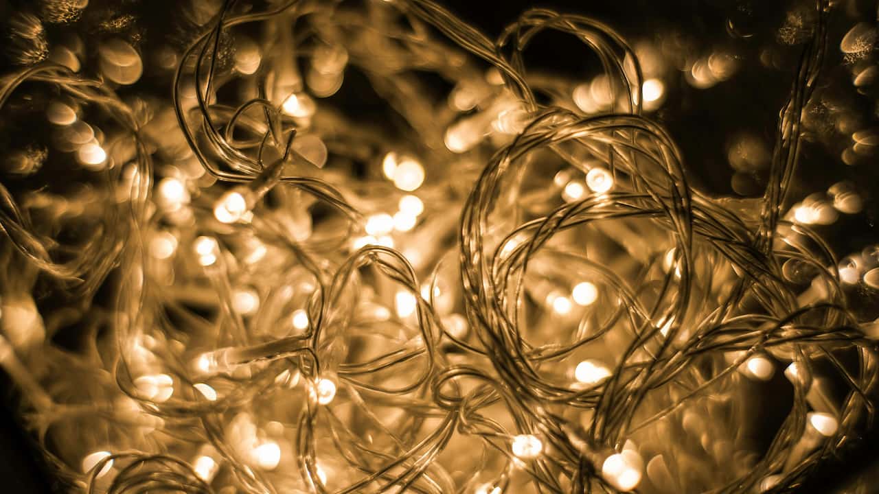 Close-up of warm yellow fairy lights, tangled in a chaotic bundle, glowing softly in the dark