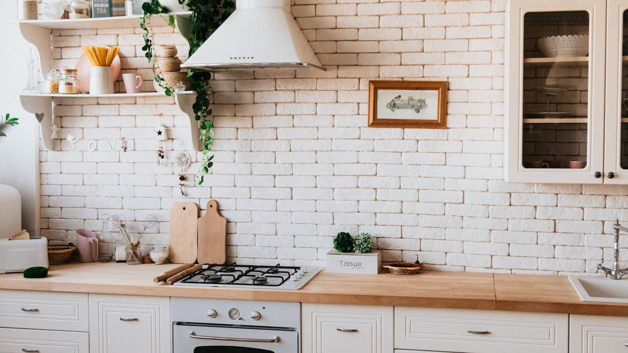 Bright, rustic kitchen with white cabinets, wooden countertops, a white brick backsplash, and neatly arranged decor items