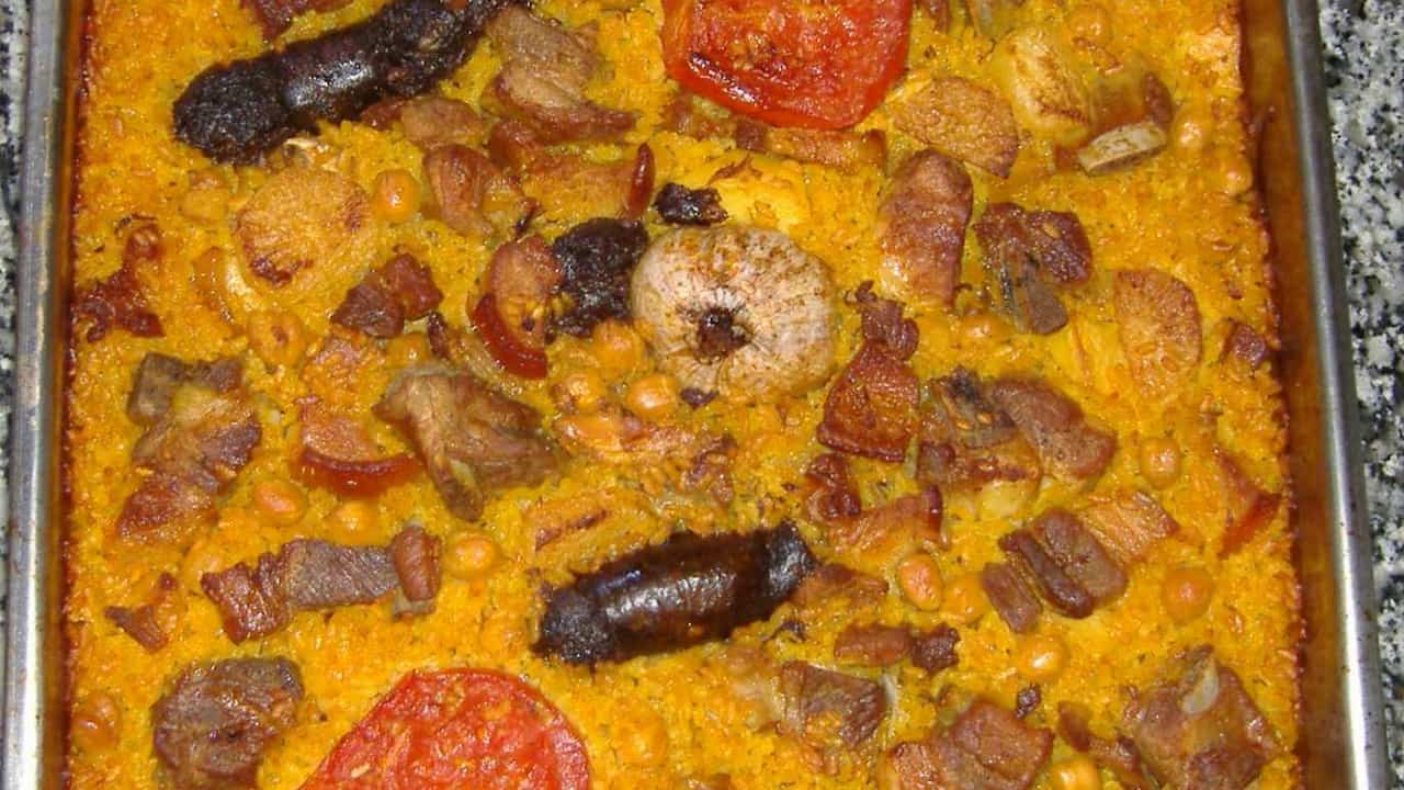 Baked rice casserole with sausages, featuring browned sausage links, chunks of pork, chickpeas