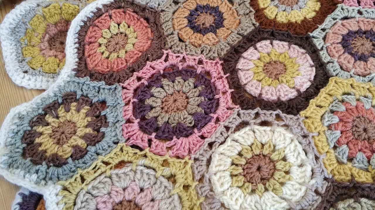 Close-up of a colorful crocheted blanket made of flower-shaped granny squares, each with a unique combination of earth-toned and pastel yarns