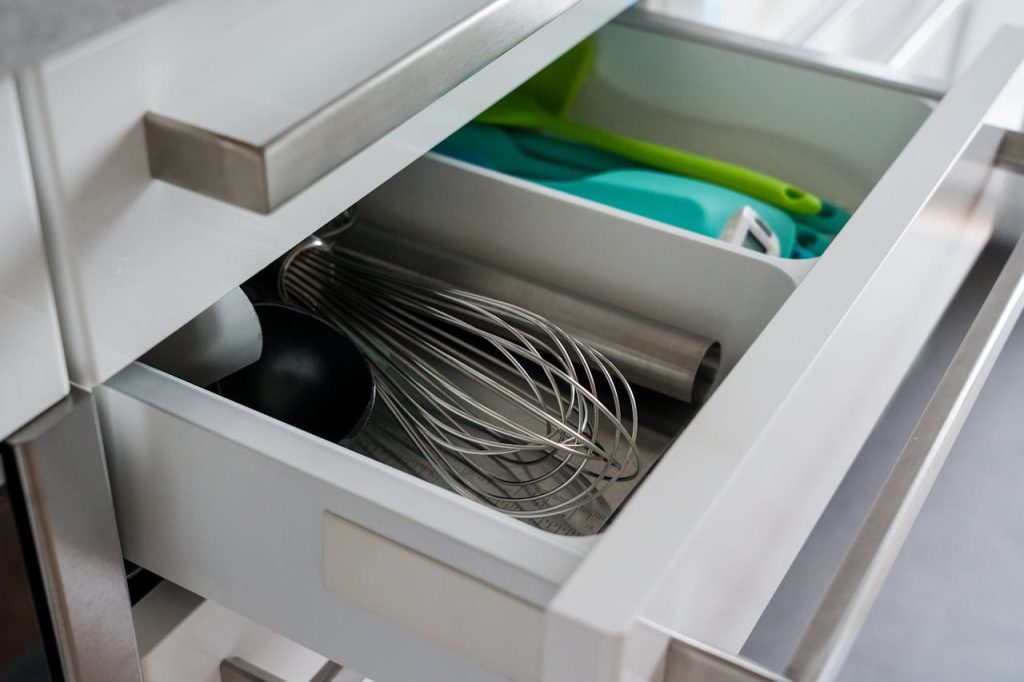 open kitchen drawer with whisk, ladle, silicone spatulas, and metal utensils neatly arranged in compartments