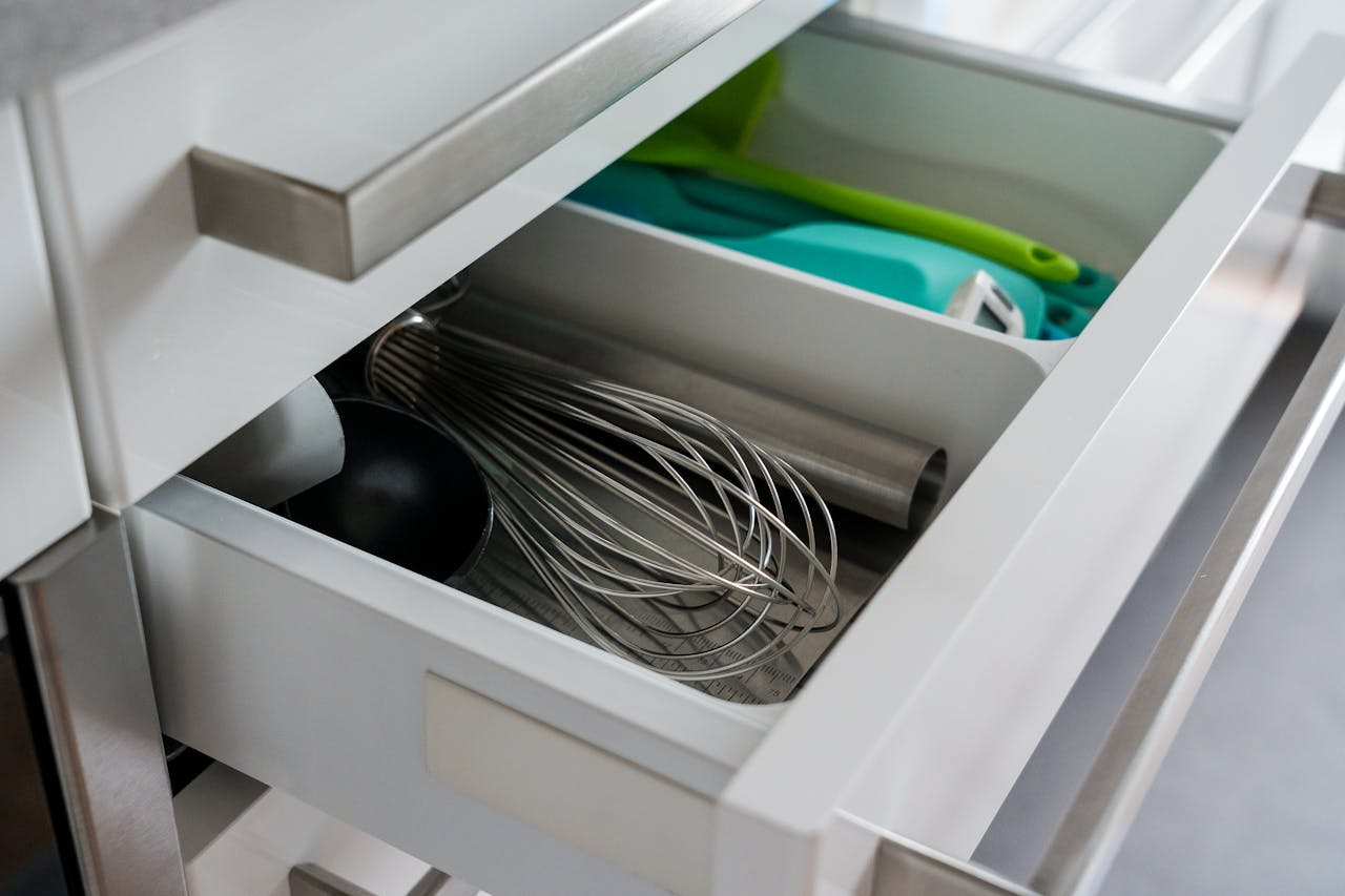 open kitchen drawer with whisk, ladle, silicone spatulas, and metal utensils neatly arranged in compartments