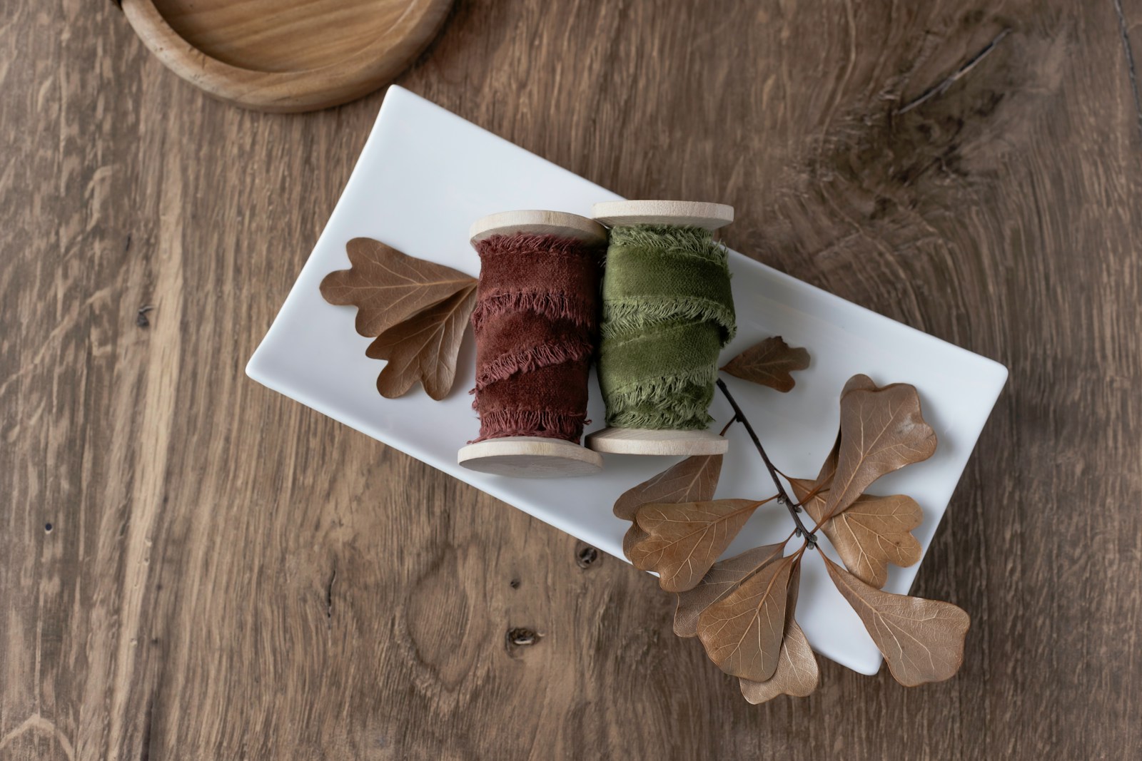 Ribbons and leaves are arranged on a white plate.
