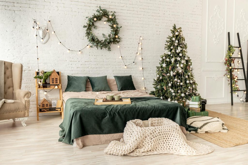 A cozy bedroom decorated with a Christmas tree and festive lights, perfect for holiday inspiration.