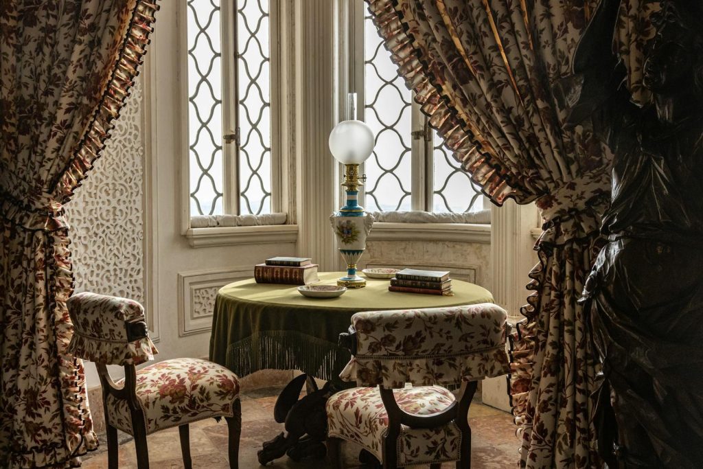 A luxurious vintage interior featuring floral drapes, antique furniture, and a decorative lamp.