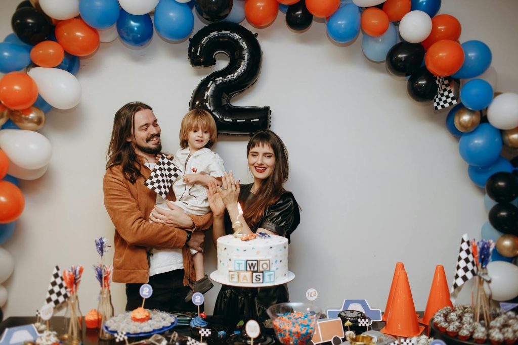 A cheerful family celebrates a child's second birthday with a colorful racing-themed party.