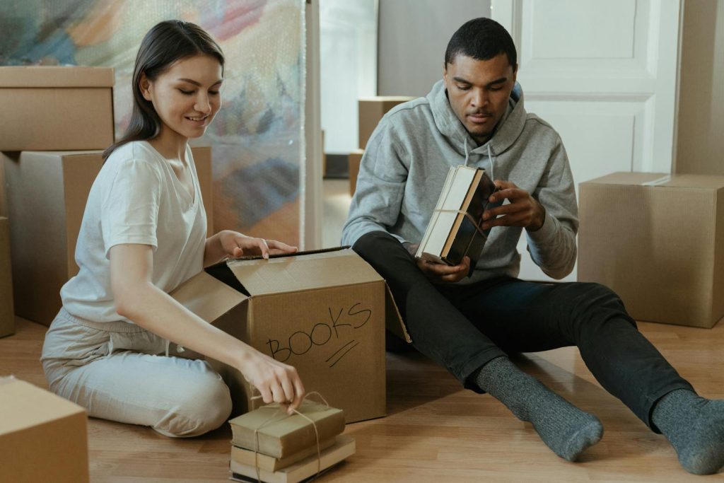 Young couple unpacking and organizing books in their new home.