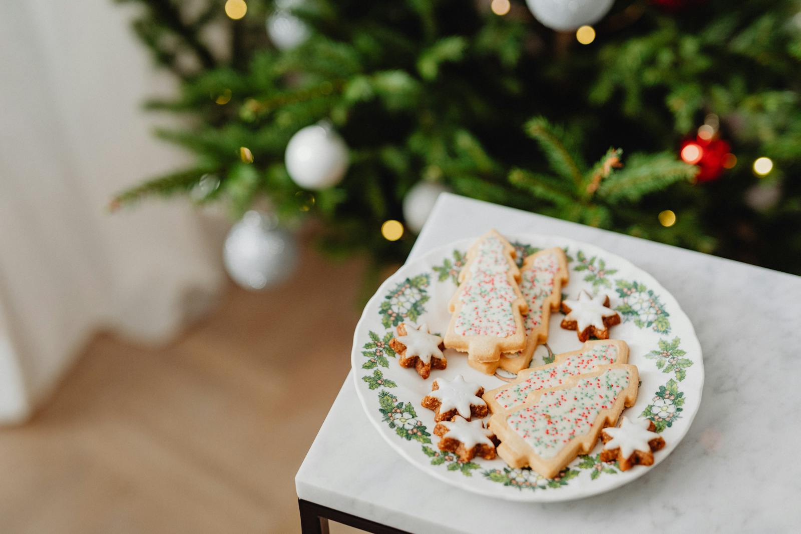 Close-up of Christmas tree cookies on a festive plate with decorations.