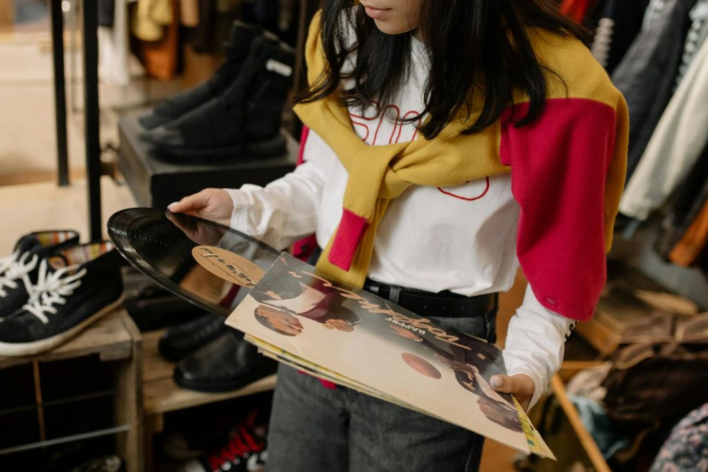 A young woman examines vinyl records in a vintage thrift store, showcasing retro style.