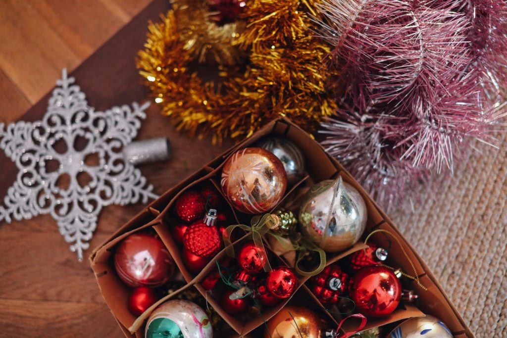 Colorful Christmas ornaments in a box with sparkling tinsel and a snowflake decoration.