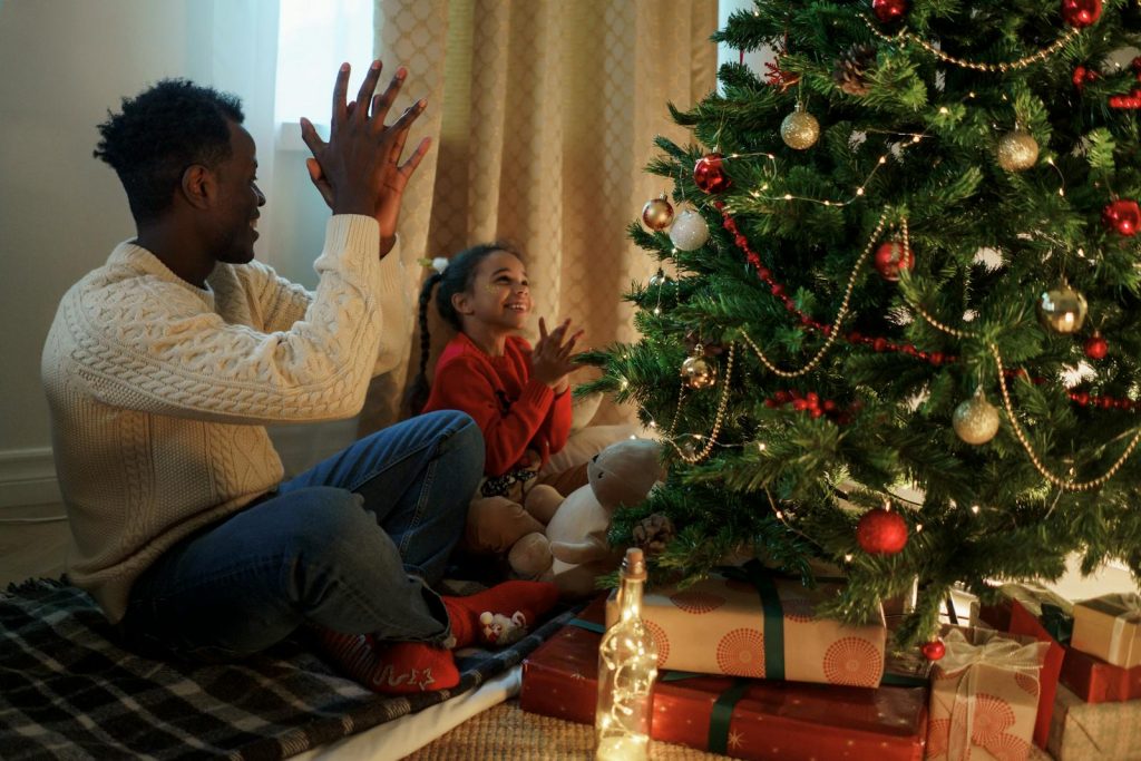 Father and daughter enjoying holiday bonding time with a Christmas tree and decorations.