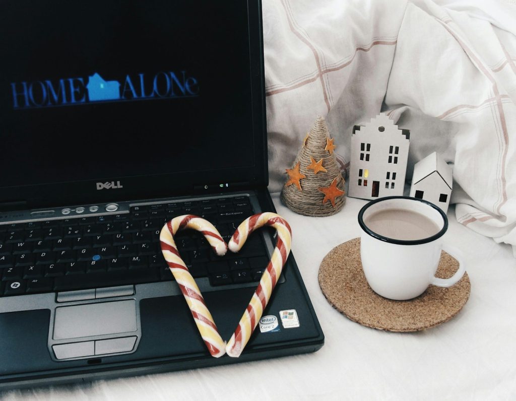 Laptop showing home alone with candy canes and hot chocolate.