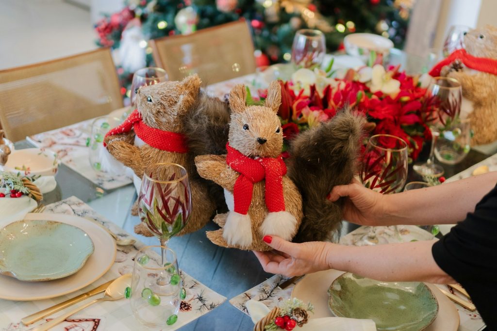 A woman is setting a table with teddy bears