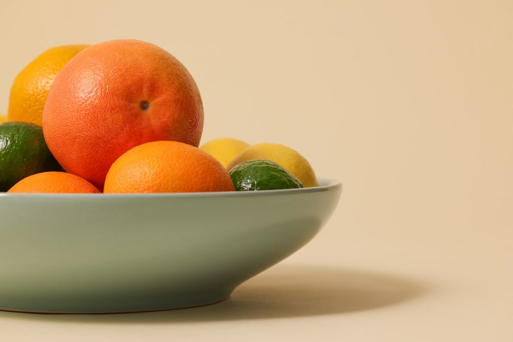 a white bowl filled with oranges and limes