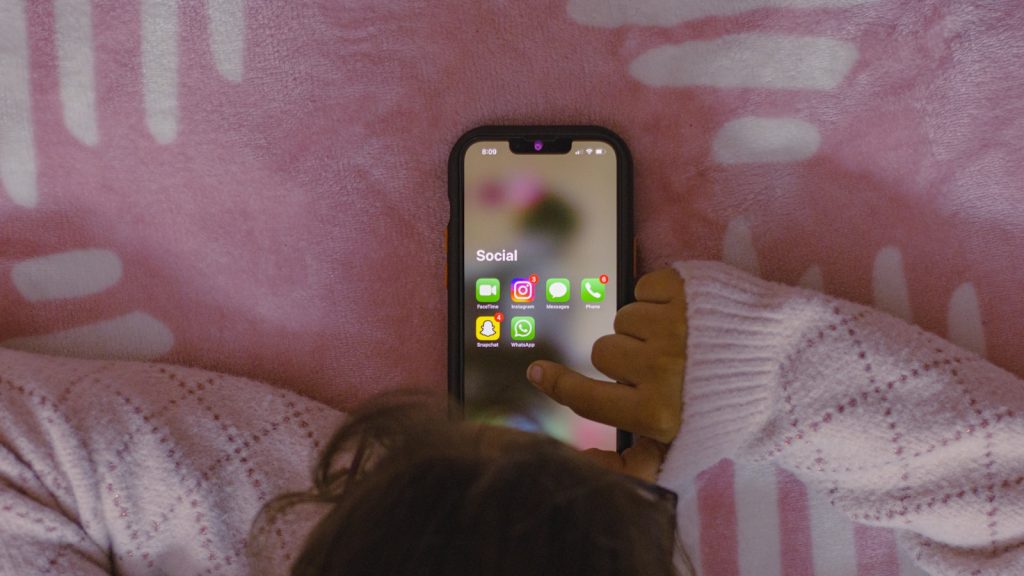 a person laying in bed holding a cell phone
