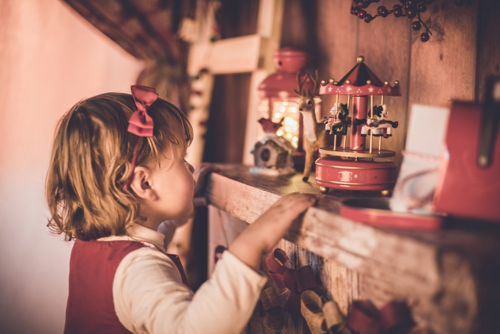 girl standing in front of carousel toy