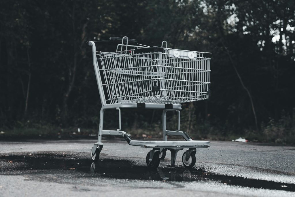 A shopping cart sitting on the side of a road