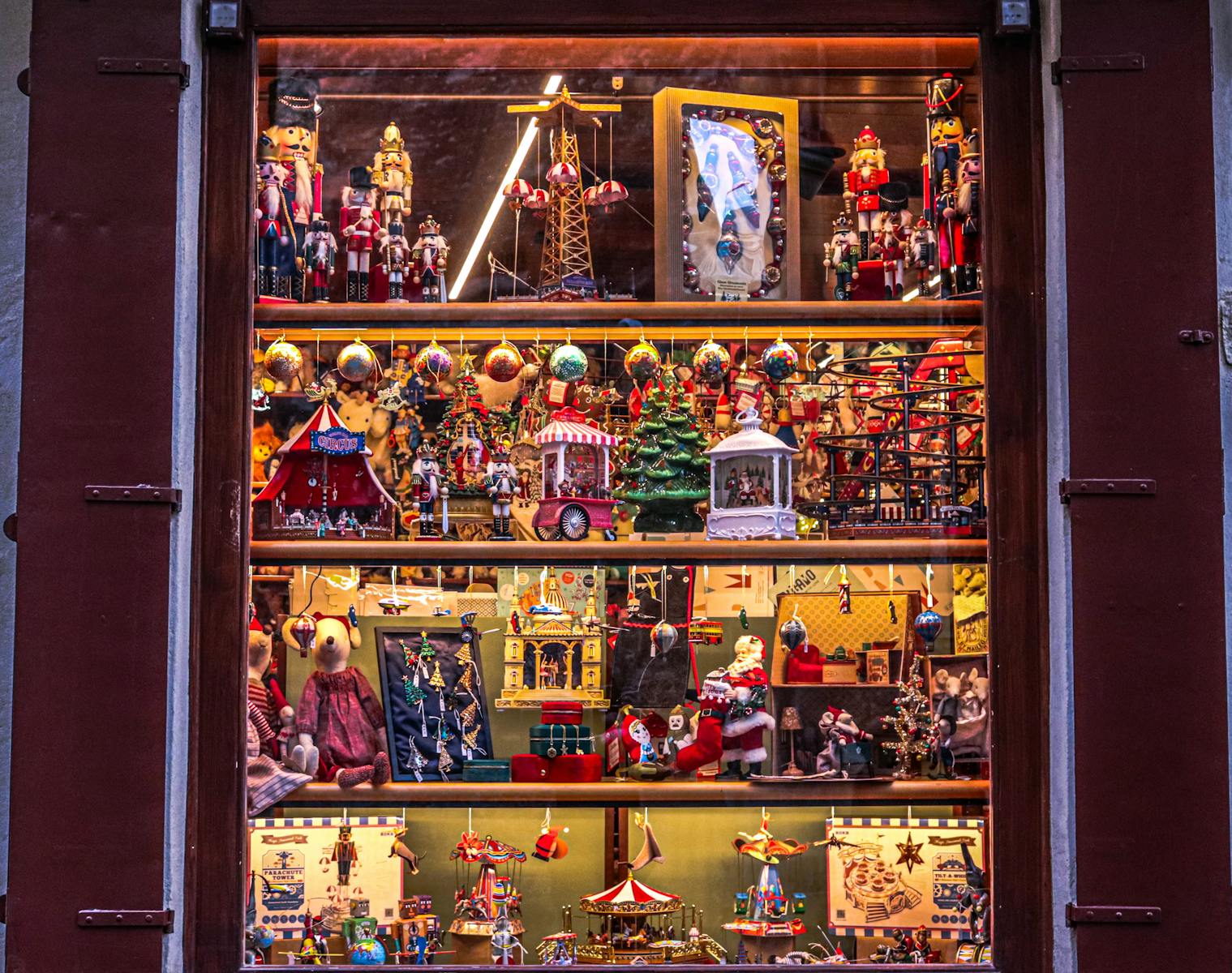 Colorful toy shop window decorated with Christmas ornaments, nutcrackers, and festive figurines.
