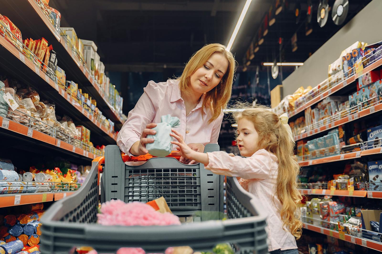 A mother and daughter shopping together in a supermarket aisle, enjoying quality time.