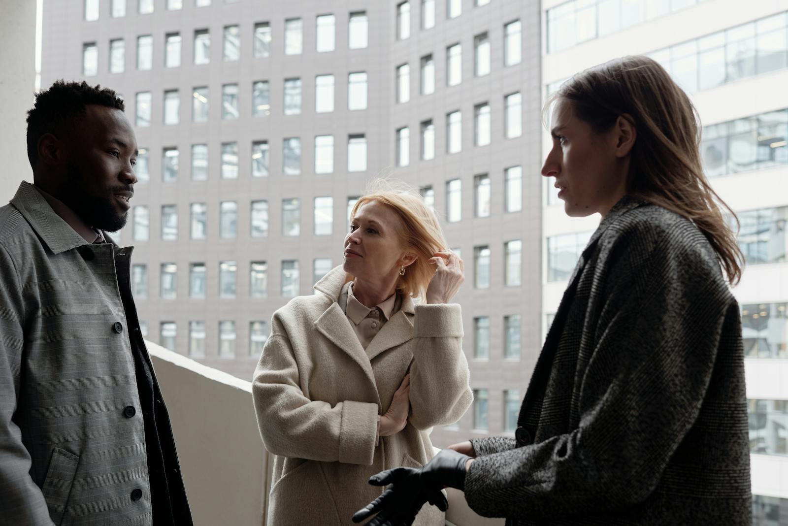 A diverse group of business professionals engaged in a discussion outside an urban building.