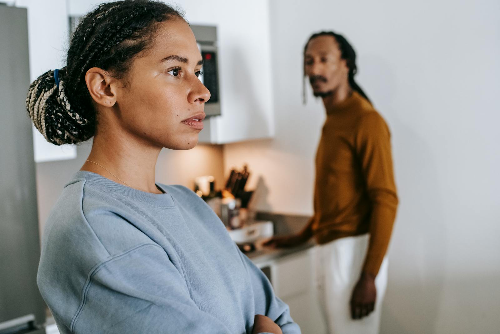 A serious young couple having a discussion in a modern kitchen setting, focusing on communication and emotions.