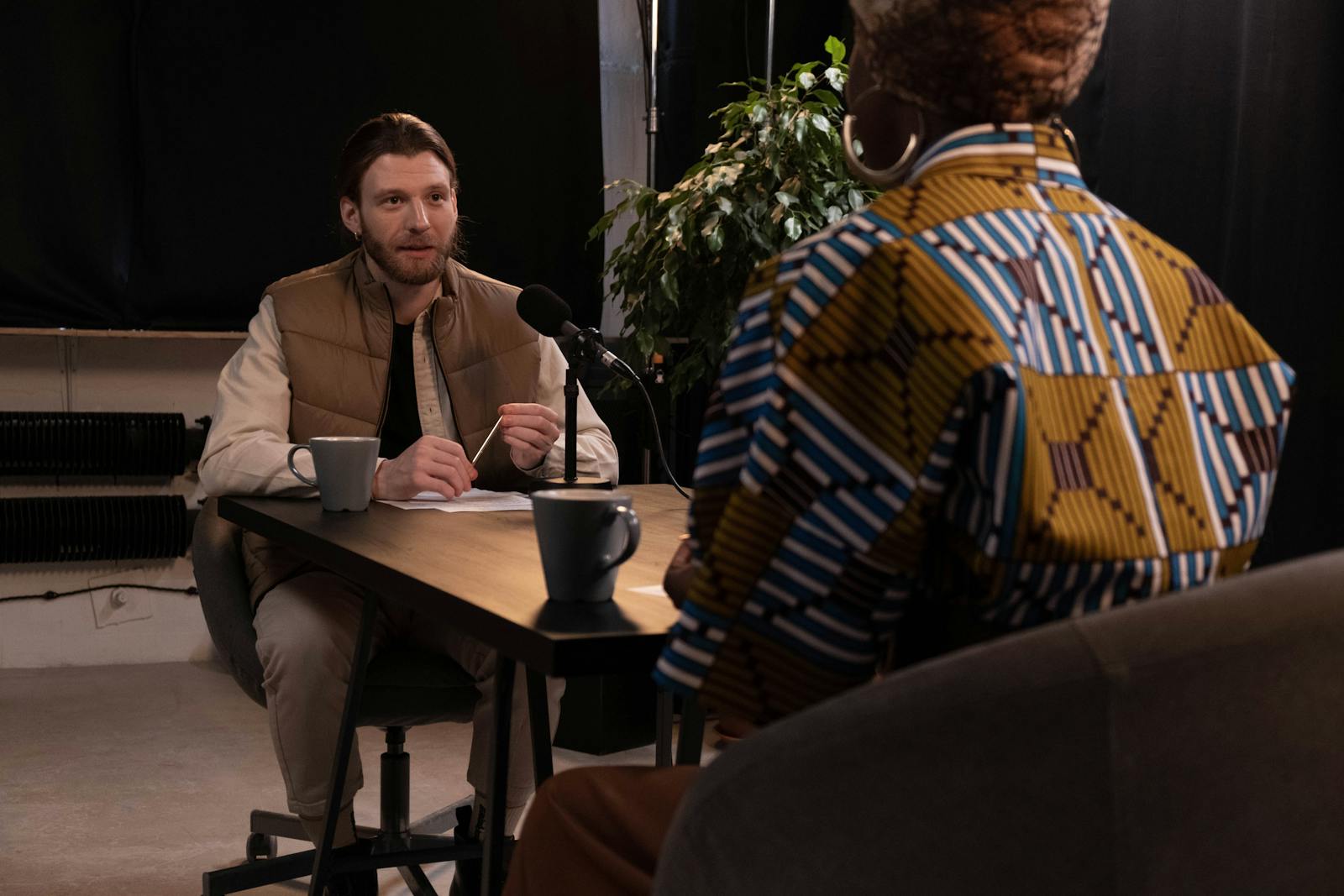 A podcast interview featuring diverse hosts in a professional studio setting with microphones and coffee mugs.