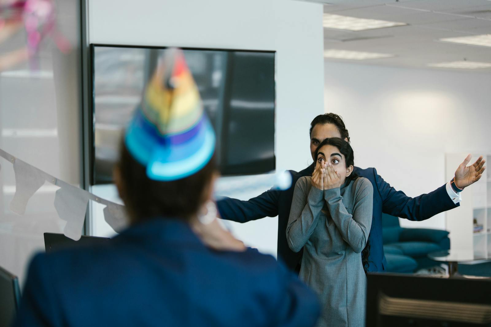 A surprised woman at an office party celebration with colleagues.
