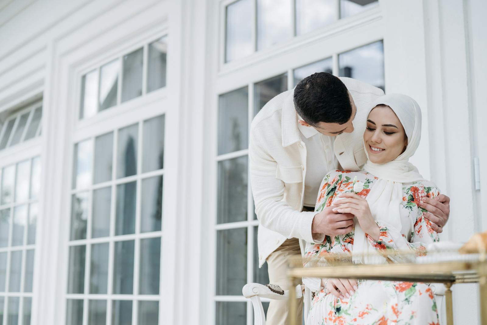 A couple enjoying a tender moment, embracing outdoors in a sunny setting.