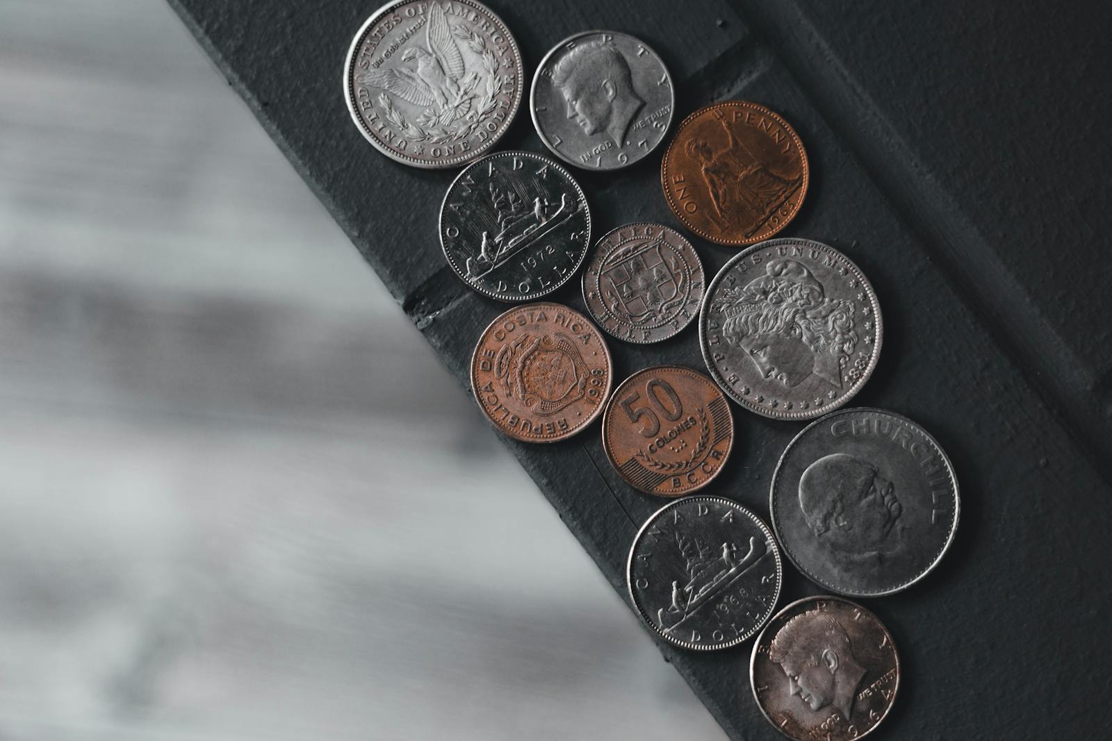 A flat lay image showcasing a diverse array of international coins laid on a textured surface.