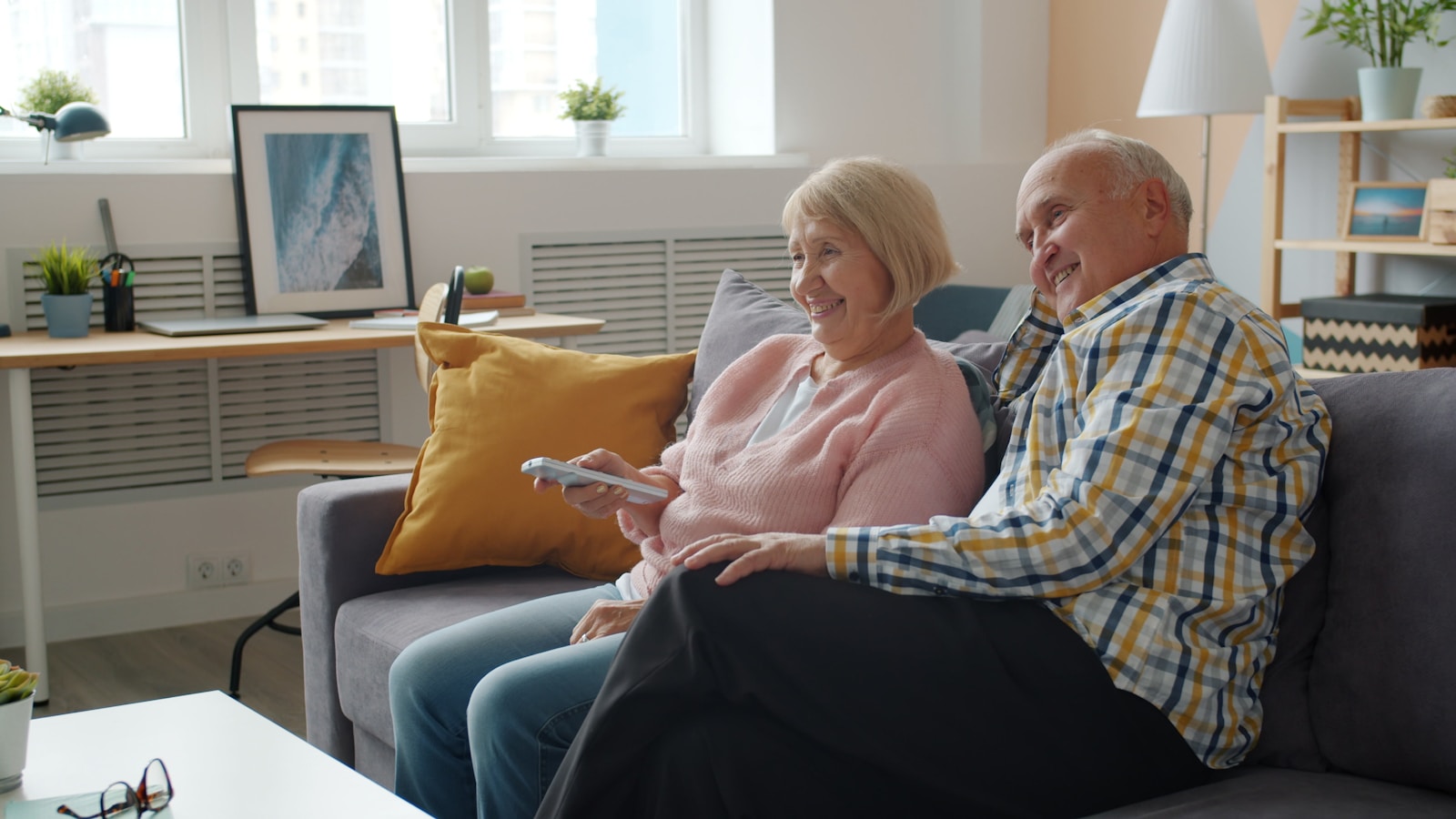 Elderly couple relaxing on a couch watching television