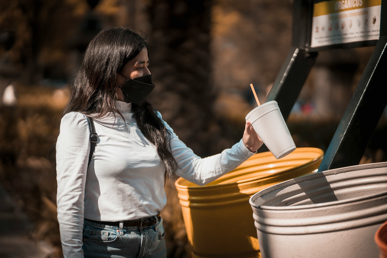 a woman in a white shirt is holding a cup