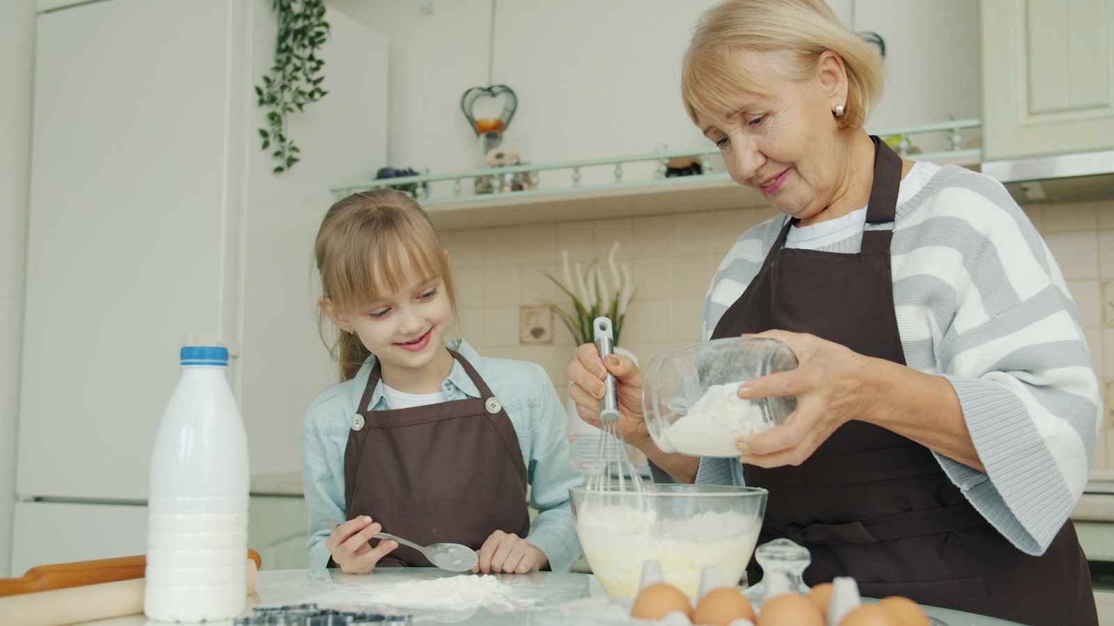 Grandmother and granddaughter baking together in a kitchen.