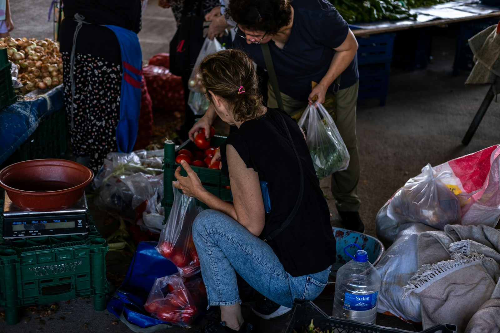 a group of people standing around a table filled with produce