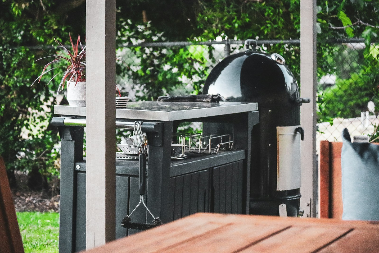a grill outside with plants in the back