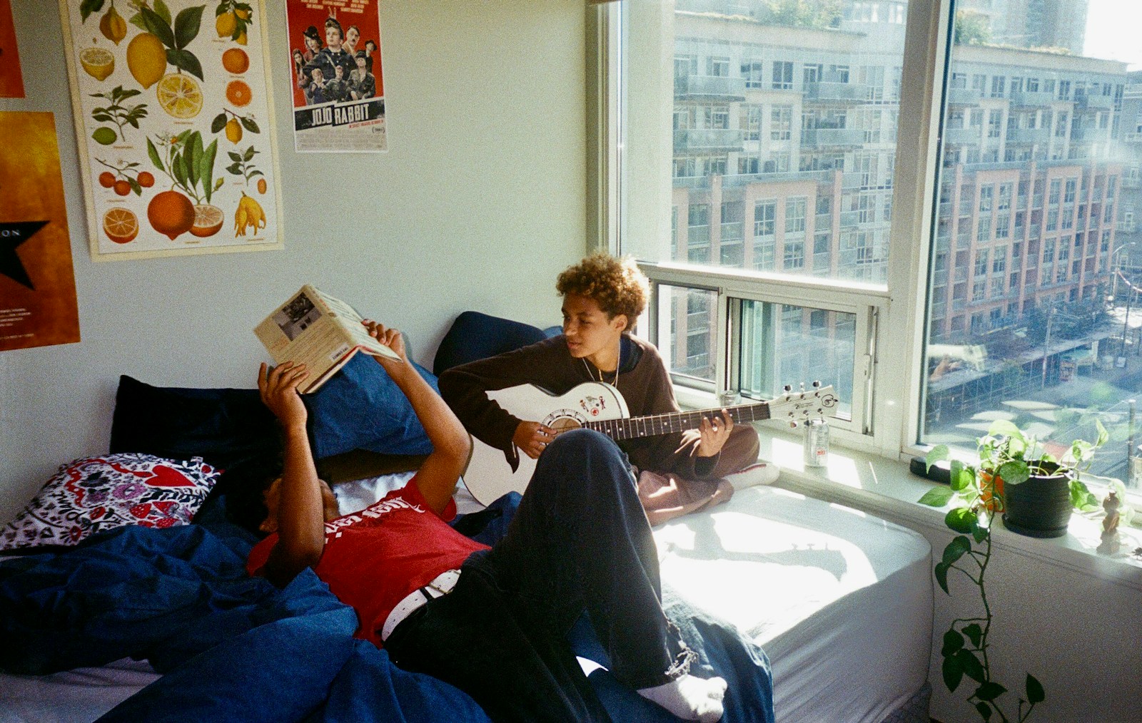 a young man sitting on a bed reading a book