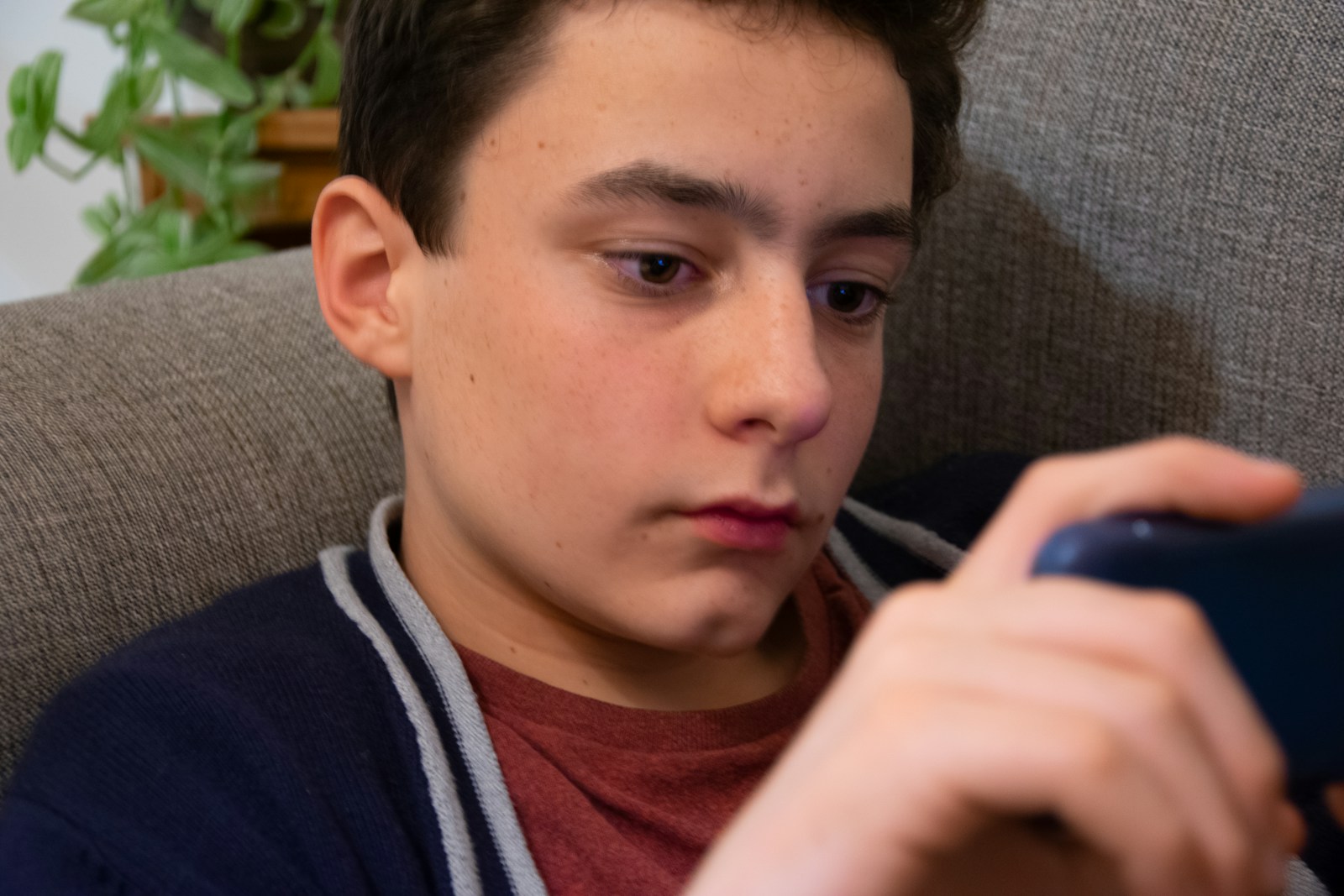 a young man sitting in a chair looking at a cell phone