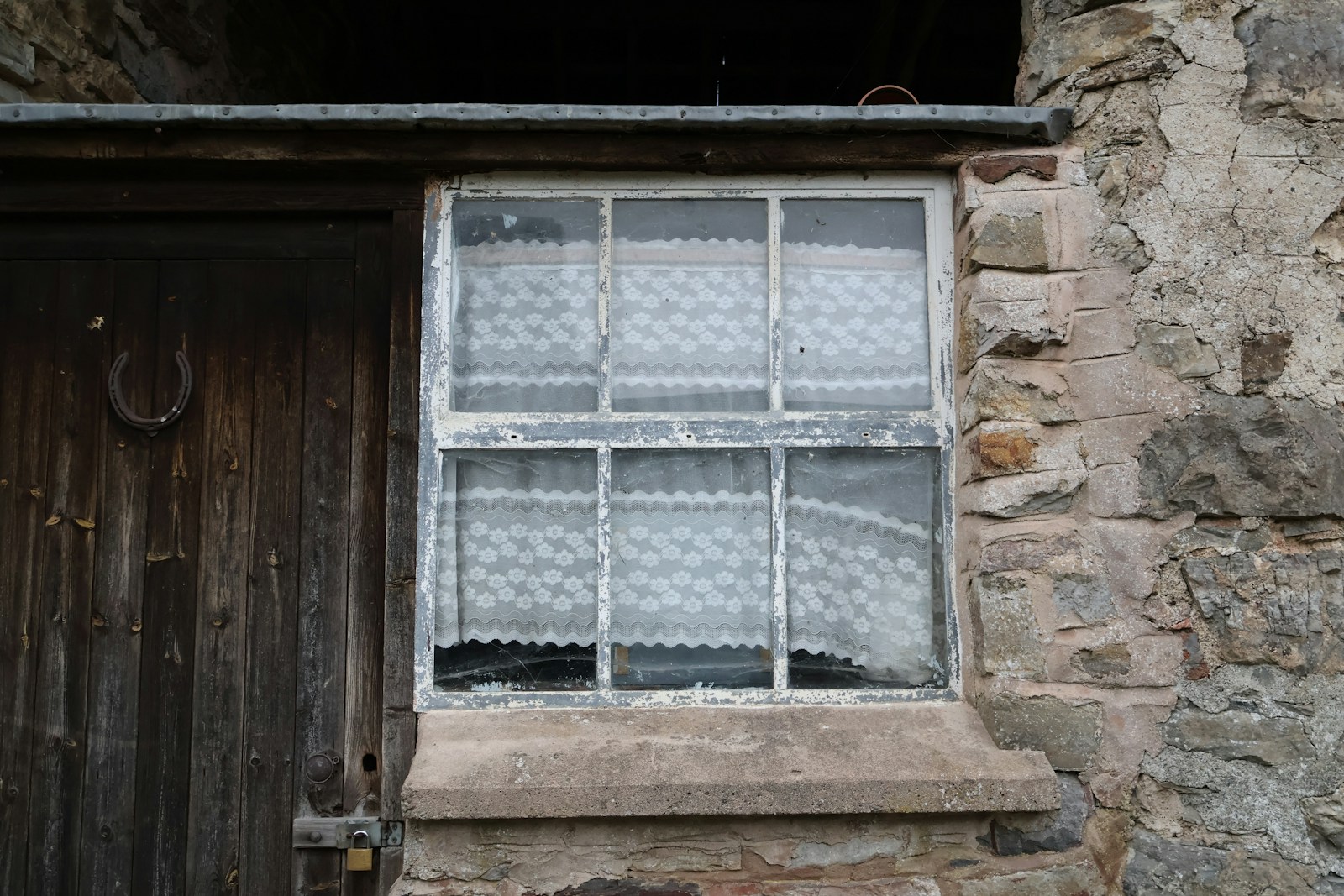 Old window with lace curtains and weathered door