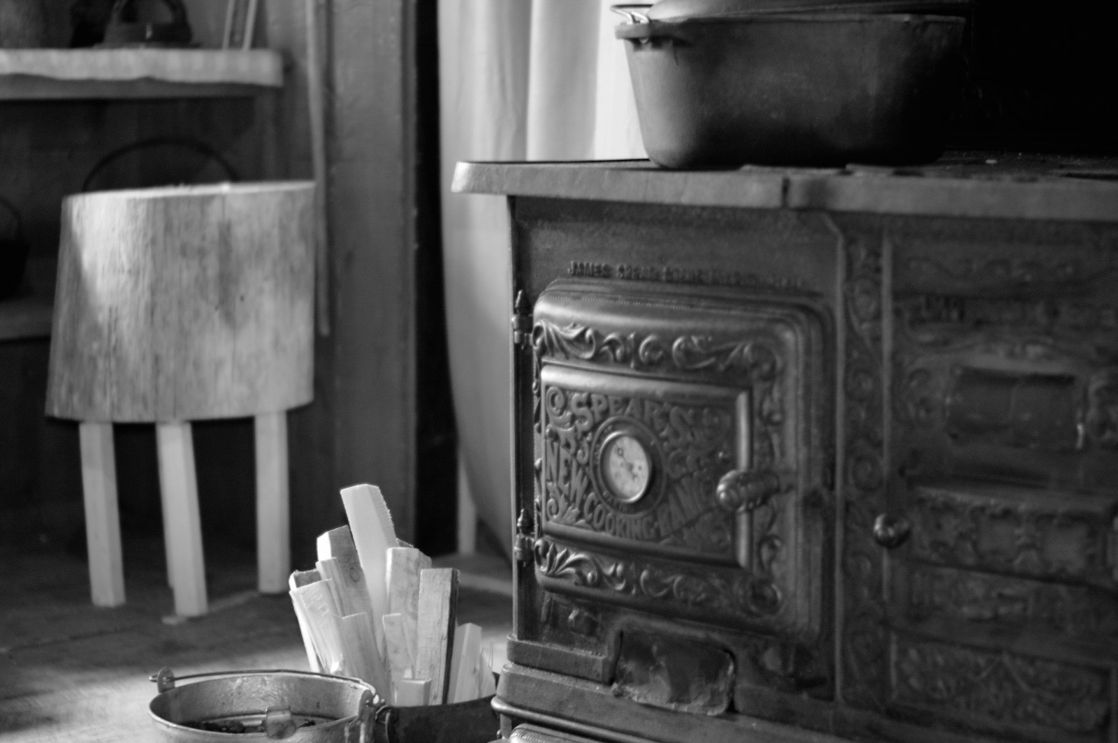 An old fashioned stove in a kitchen next to a chair