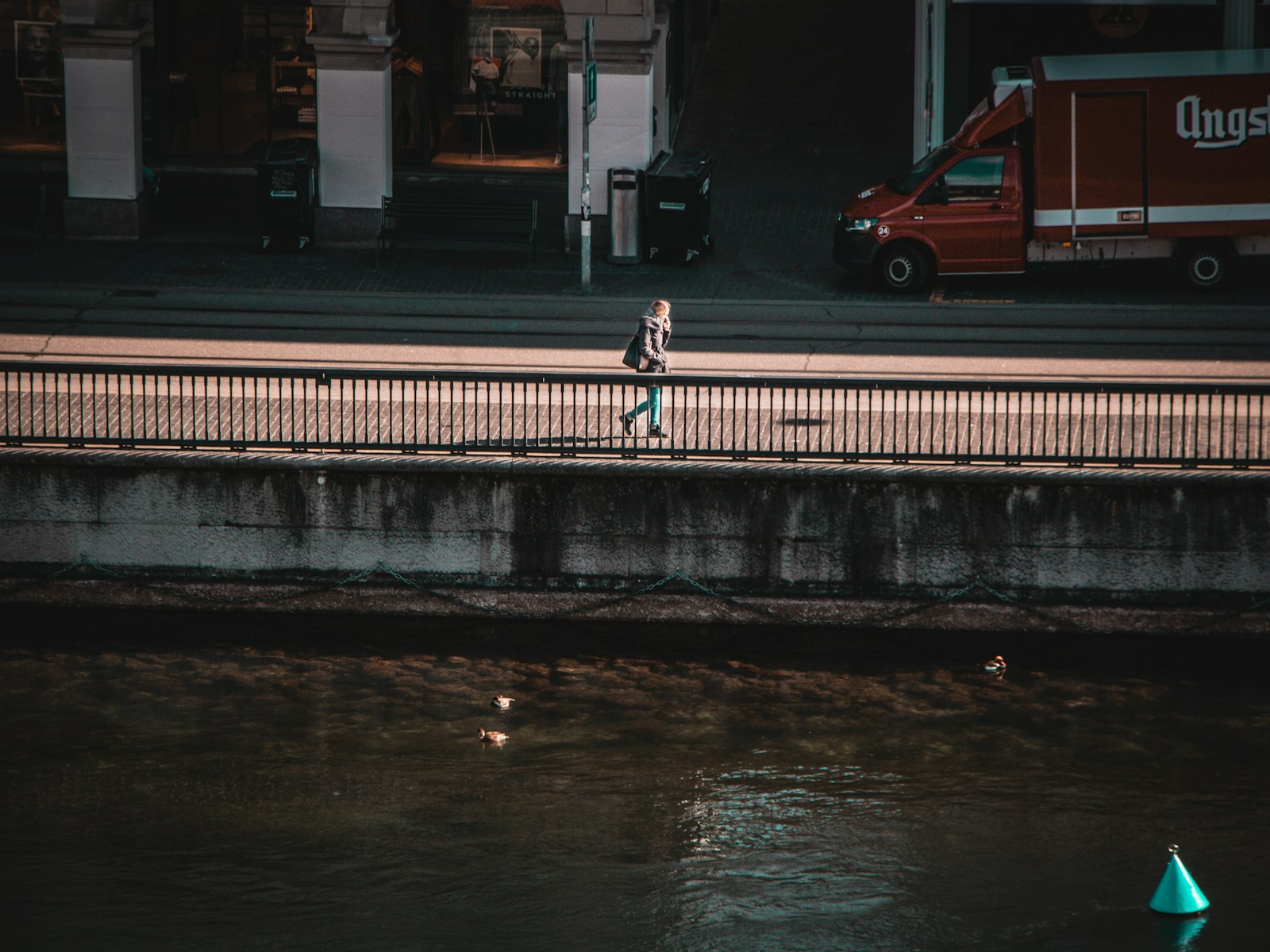 person in black jacket and black pants walking on sidewalk during night time