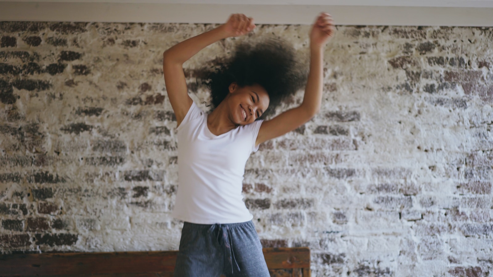 Young woman with afro dancing joyfully in room