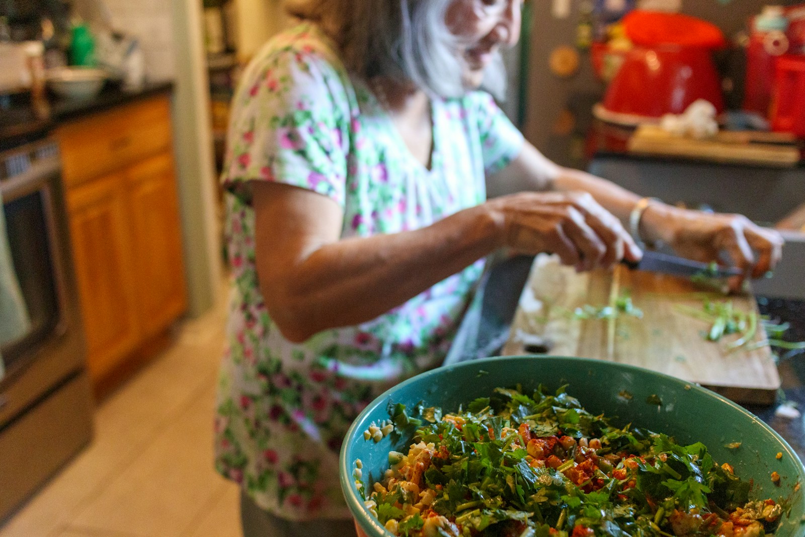A woman cutting up a salad in a kitchen