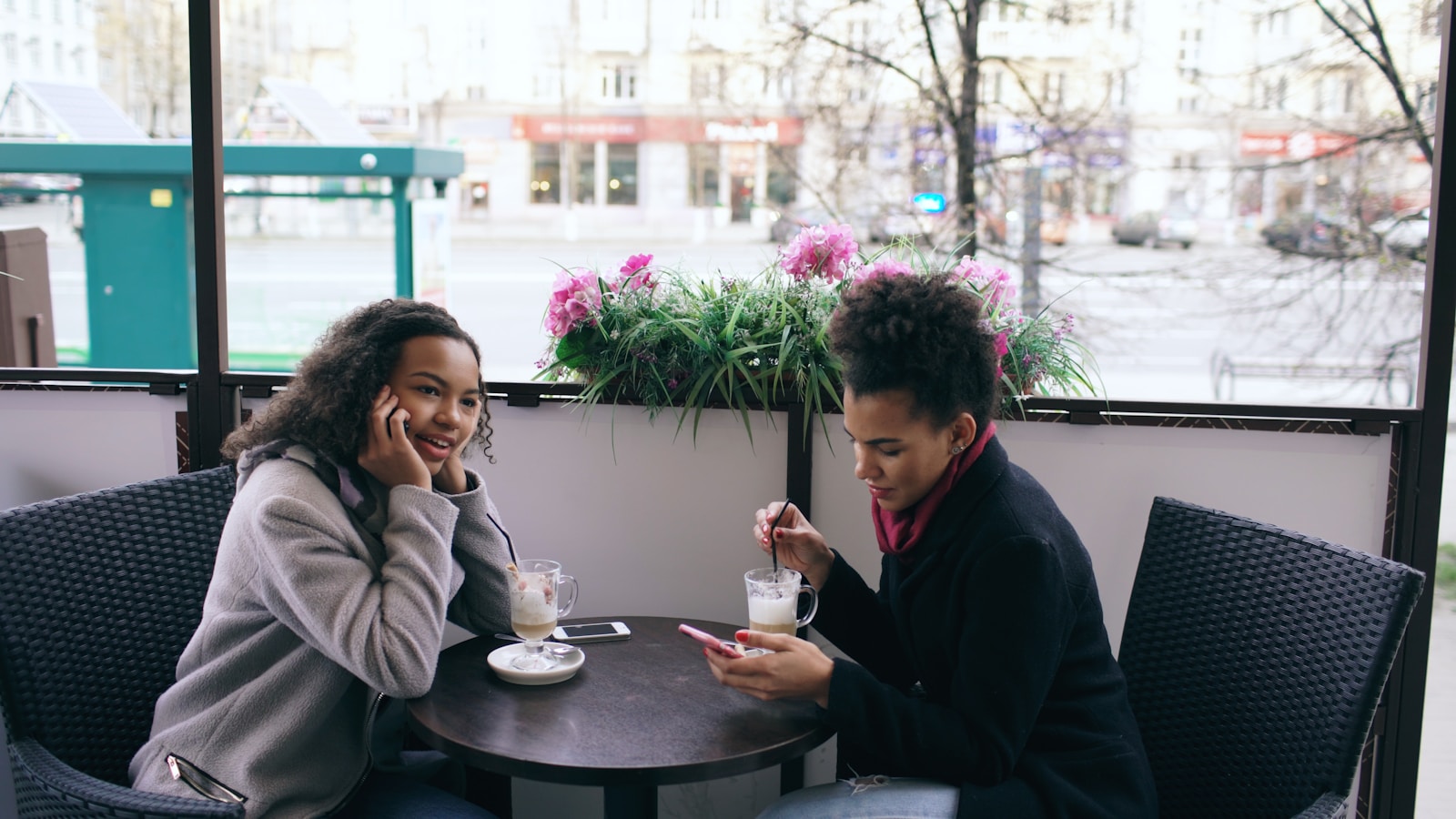 Two women sitting at a cafe table outdoors.