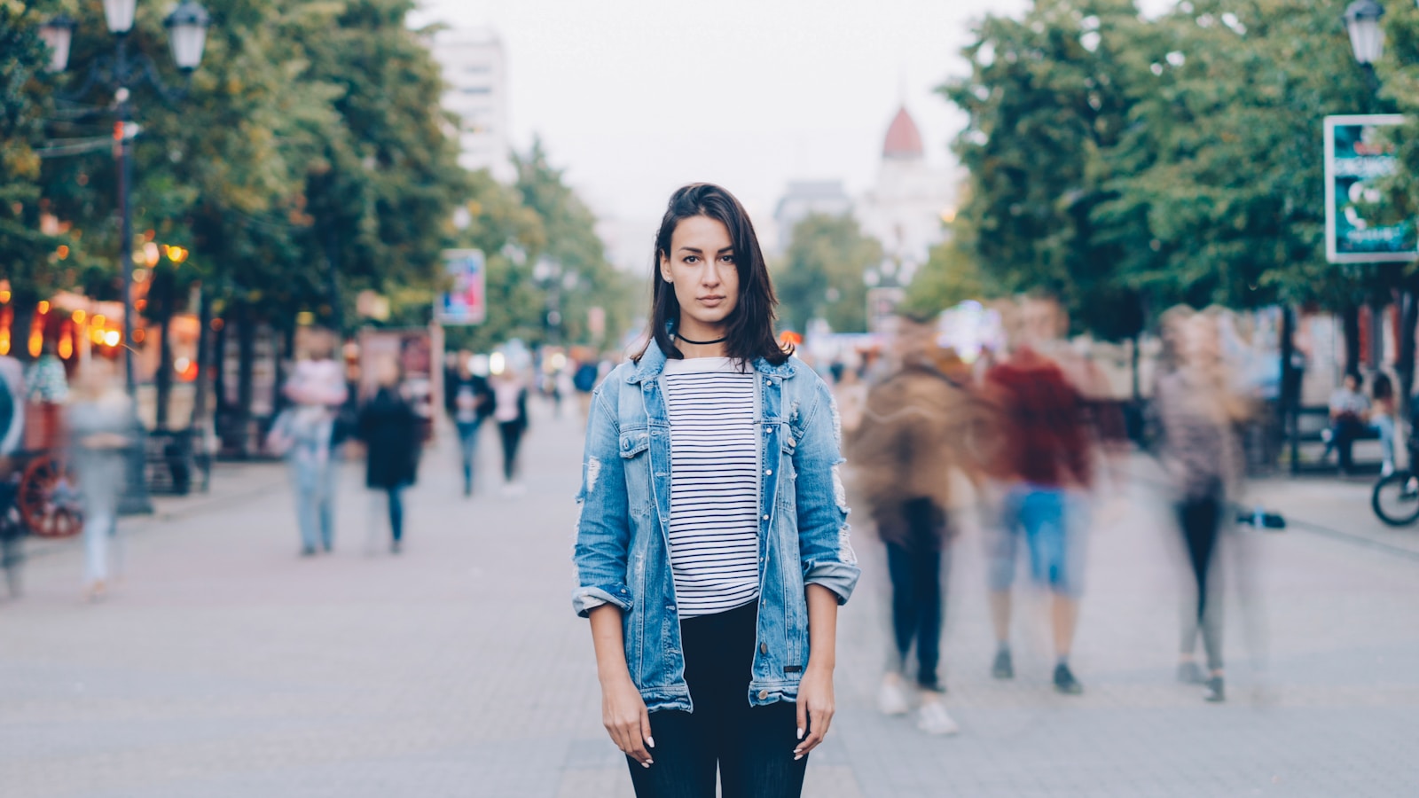 A woman stands still in a busy street.