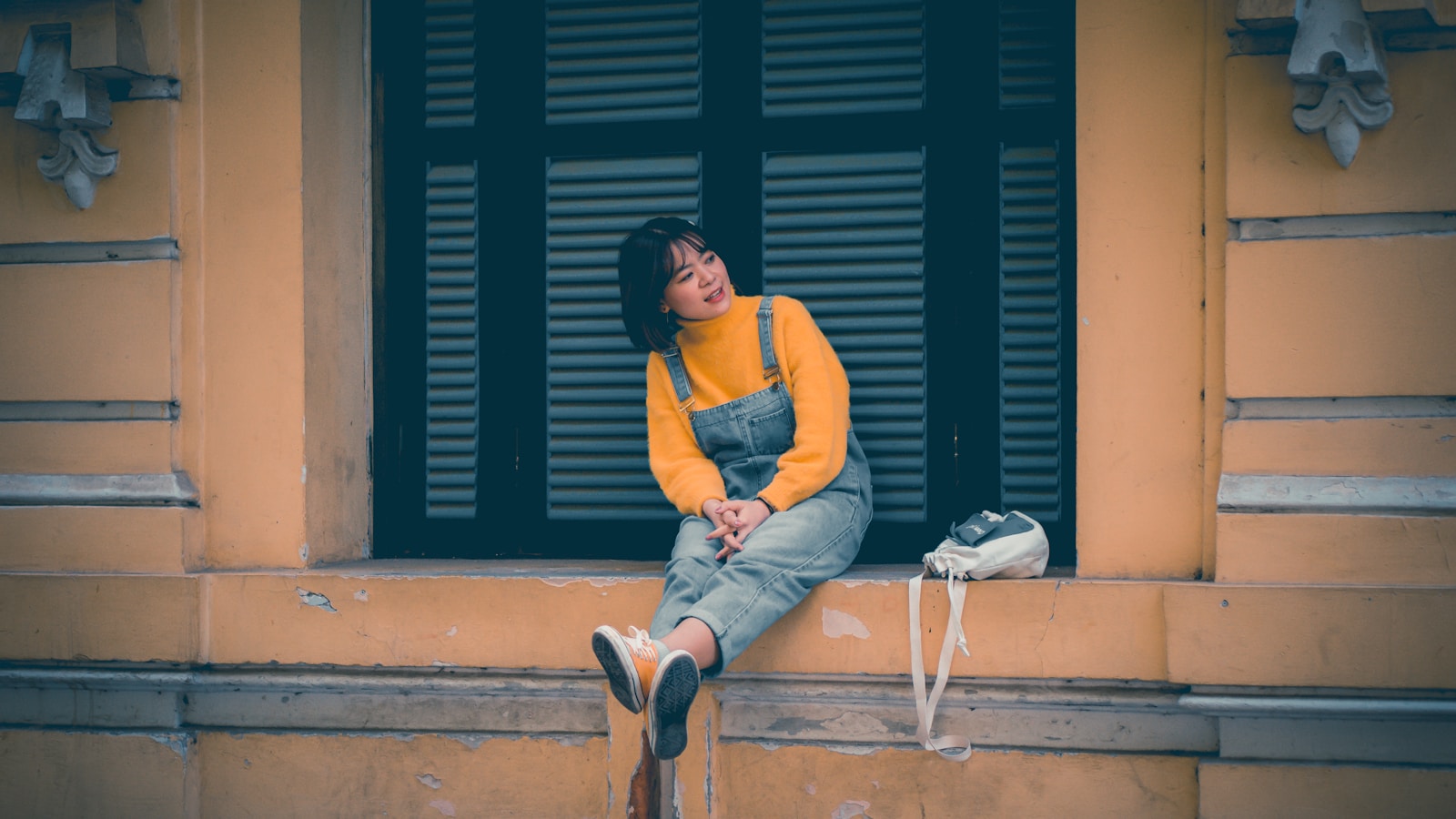 a woman sitting on a ledge of a building