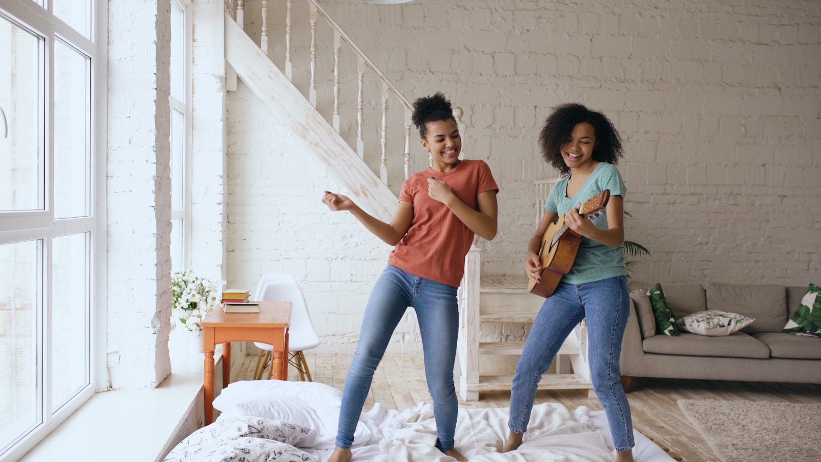 Two women dancing and playing guitar indoors.