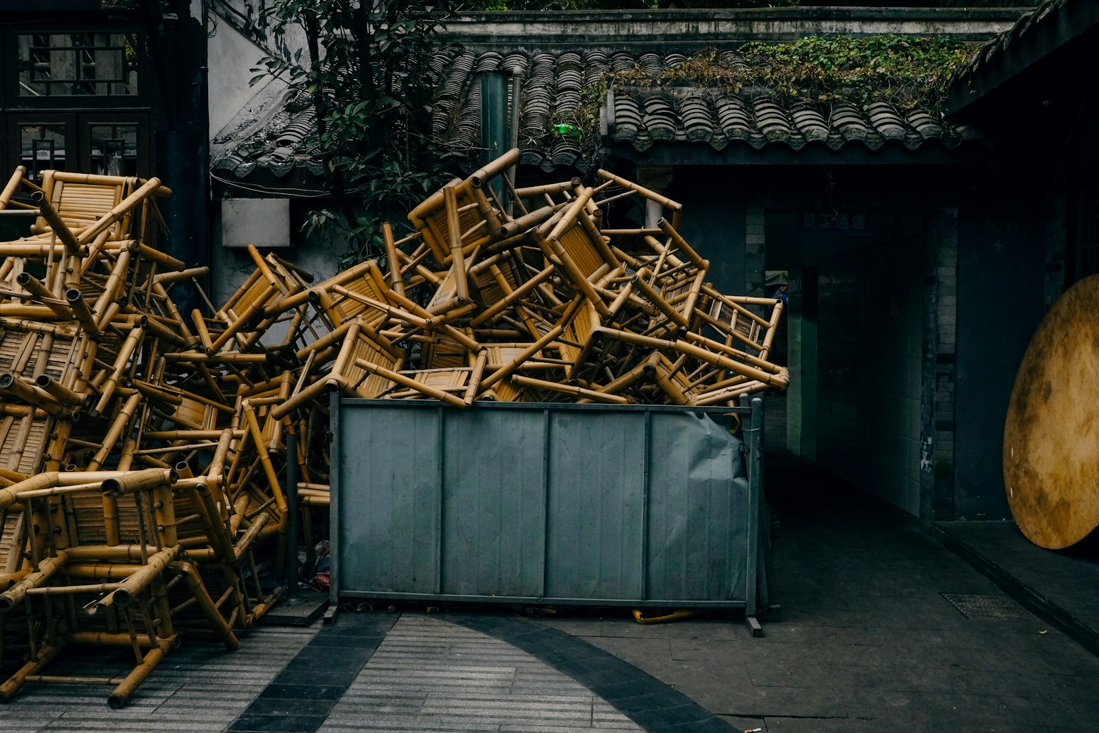 Chairs piled high in a metal container.