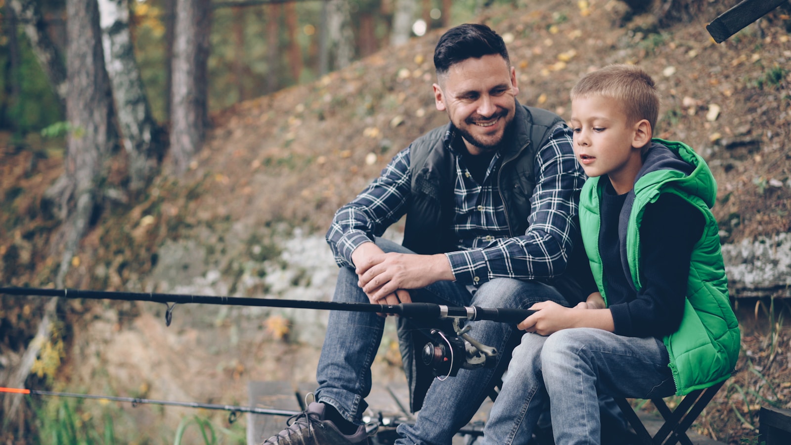 Father and son fishing together at a lake.