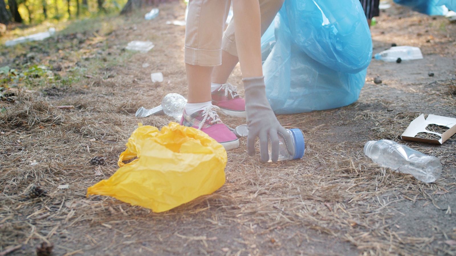 Person picking up trash with a blue bag